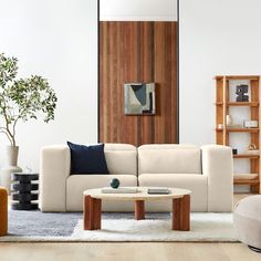 a living room with white couches and wooden shelves on the wall, coffee table in front of it