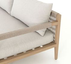 a white couch with two pillows on it's backrests and a wooden frame