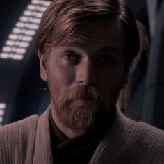 a close up of a person with a beard and wearing a cardigan sweater in front of a star wars background