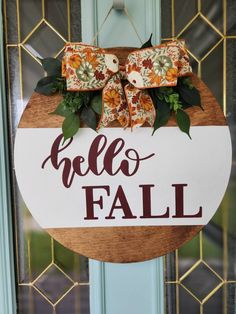 a wooden sign that says hello fall hanging on the front door with flowers and leaves