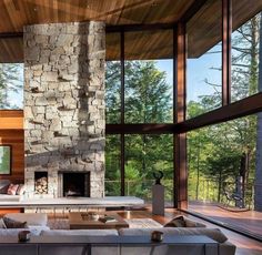 a living room with large windows and a stone fireplace