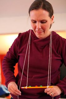 a woman in a red sweater is holding a pencil and an abacus on a string