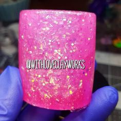 a person in purple gloves holding up a pink and gold flaked cup with the words oath love clay works on it