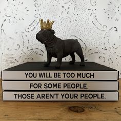 two books with a dog figurine sitting on top of them, one is wearing a crown