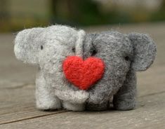 an elephant with a red heart on its trunk sitting on a wooden surface in front of the camera