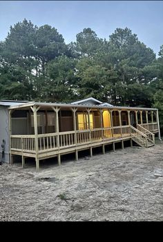 a mobile home sits in the middle of a dirt lot next to some pine trees