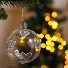 a glass ornament hanging from a christmas tree with gold lights in the background