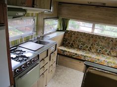 a kitchen with a stove top oven next to a sink and window in a trailer