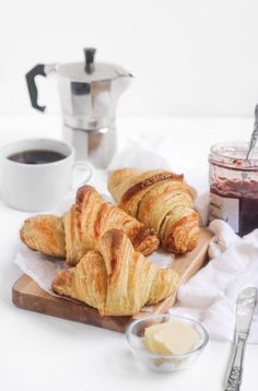 croissants on a cutting board with butter and syrup next to them,