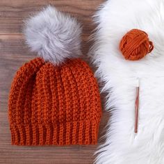 an orange knitted hat next to a ball of yarn