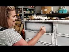 a woman is painting an old dresser in her home shop with white paint on the drawers