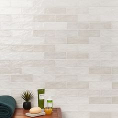 a wooden table topped with towels and other items on top of a white tiled wall