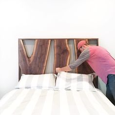 a man in pink shirt and jeans leaning on bed with headboard made out of wooden letters