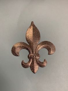 a metal fleur de lis on a white surface