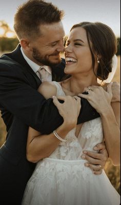 a bride and groom embracing each other outside