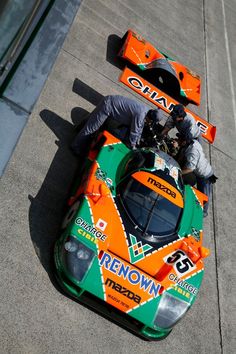 two men working on an orange and green race car