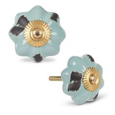 two blue and black flower shaped knobs with gold accents on each side, set against a white background