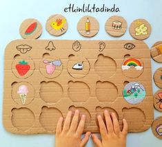 a child's hand is touching a wooden board with pictures on it