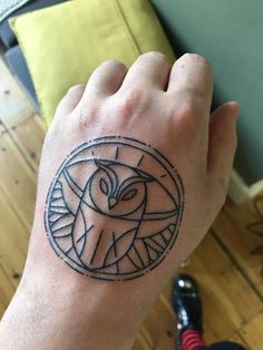 a person's hand with an owl tattoo on the middle of their left arm