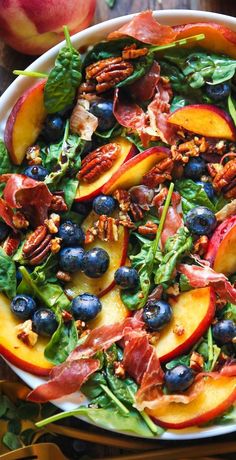 a salad with peaches, blueberries and pecans in it on a plate