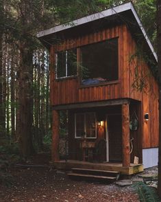 a small wooden cabin in the woods with trees around it and lights shining on the windows