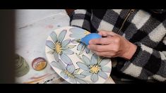 a person is holding a plate with blue flowers on it and the other hand has a plastic object in front of them