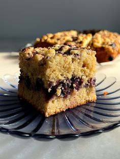 two pieces of blueberry crumb cake sitting on a glass plate next to each other