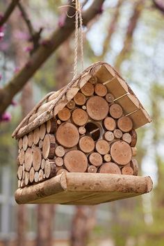 a birdhouse made out of logs hanging from a tree