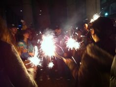 a group of people standing around each other holding sparklers