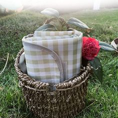 a basket filled with cloths and flowers sitting on top of a grass covered field