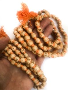 Neem japa mala made from Neem beads, hand knotted on orange cotton thread, and printed in Hindi script with "Radhe Radhe" on each bead. (Printing is not so great; barely legible in some cases, but the thought is there!) The beads are approximately 8mm or 10mm (two sizes) and end with small orange-colored cotton tassel. Choose from two sizes small 7- 8mm beads ($4.50) large 9 - 10mm ($5.50) Spiritual Wooden Beads Mala For Festival, Bohemian Mala With Wooden Beads For Festivals, Handmade Holistic Mala For Festival, Holistic Handmade Mala For Festivals, Traditional Mala With 108 Beads For Festival, Holistic Mala With Round Beads For Festival, Holistic Mala For Festival With Round Beads, Holistic Festival Mala With Round Beads, Traditional Orange Beads For Gifts