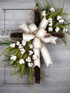 a wreath with white flowers and grass on a wooden surface, ready to be used as an ornament