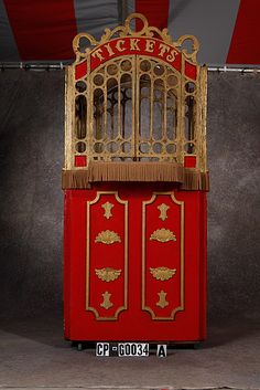 an old fashioned red and gold ticket booth