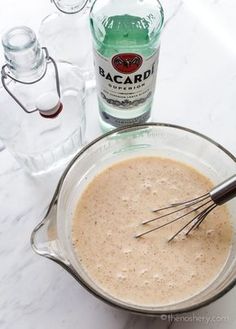 a mixing bowl filled with batter and whisk next to a bottle of bacardi