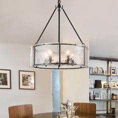 a chandelier hanging over a dining table in a room with pictures on the wall