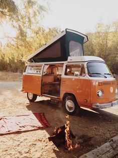 an orange and white van is parked in the dirt