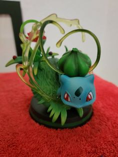 a green and blue figurine sitting on top of a red rug