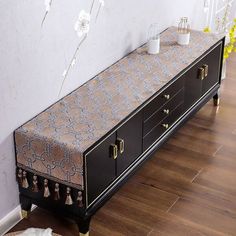 a black and gold sideboard with tassels on the drawers in an empty room