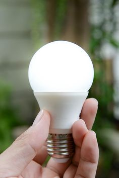 a person holding up a light bulb in their hand