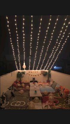 a living room filled with lots of furniture and lights hanging from the ceiling above it