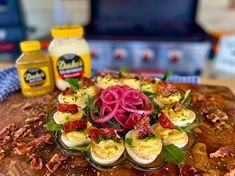 an assortment of deviled eggs on a cutting board with red onions and other ingredients