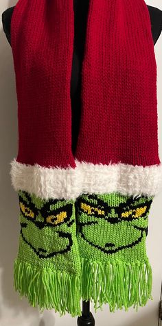 a pair of red and green knitted mittens on top of a mannequin's head