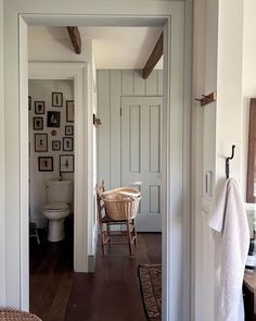 an open door leading to a bathroom with pictures on the wall and a wicker chair