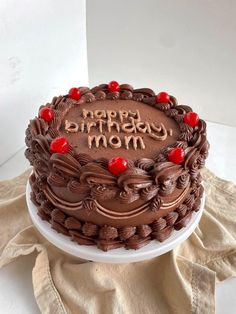 a chocolate birthday cake with the words happy birthday mom written on it and cherries