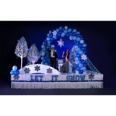 two people standing on top of a stage with snowflakes and trees in the background