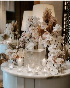 a table topped with lots of vases filled with flowers and candles on top of it