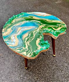 a coffee table with green and gold paint on it's top, sitting in the middle of a parking lot