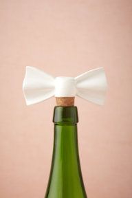 a green bottle with a white bow on it's top and cork stopper