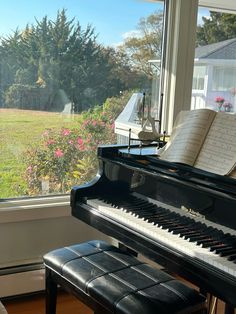 a piano sitting in front of a window next to a bench