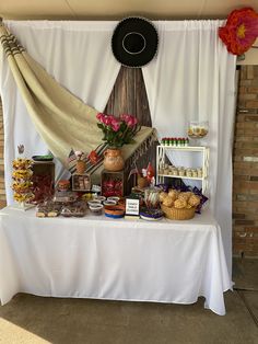 a table topped with lots of food under a white canopy next to a brick wall